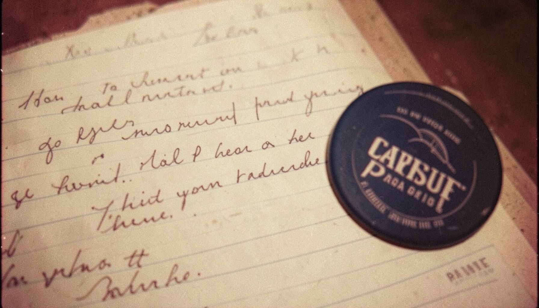 A close-up analog photograph of a handwritten letter on lined paper beside a campaign button, warm cream and navy tones, soft grain.